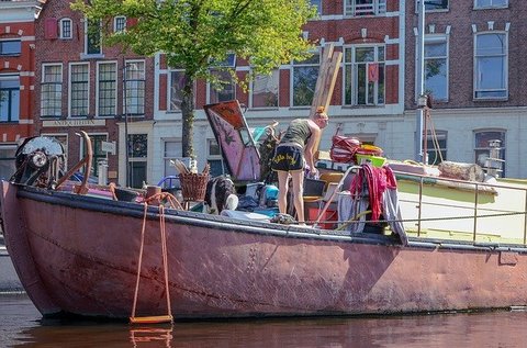 In de binnenstad van Groningen staat een vrouw op een boot aan het opruimen
